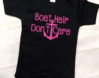 Può includere: Body nero per neonato con un'ancora rosa e il testo "Boat Hair Don't Care".