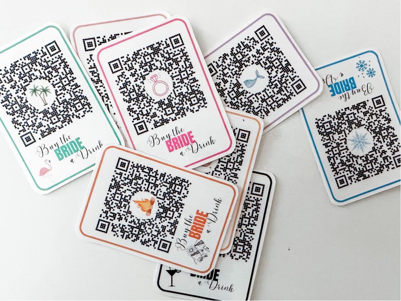 May include: A set of eight white cards with black and white QR codes. Each card has a different icon in the centre of the QR code, including a palm tree, a ring, a fish, a snowflake, a campfire, a martini glass, and a mermaid. The text "Buy the Bride a Drink" is printed on each card.