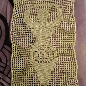 Könnte beinhalten: Eine beige gehäkelte Deckchen mit einem floralen Muster. Die Deckchen ist aus einem zarten, durchbrochenen Muster gefertigt.