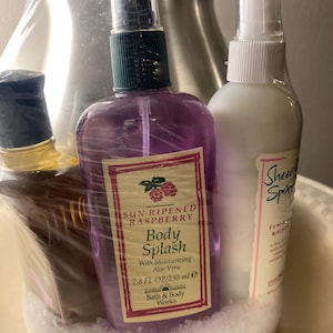 May include: A gift set featuring three Bath & Body Works products. The set includes a purple body splash bottle with a raspberry label, a white bottle, and a bottle with a dark cap. The body splash is 7.8 fl oz / 230 ml.