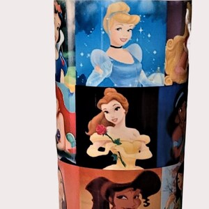 May include: A blue and yellow water bottle featuring images of Disney princesses. The bottle has a blue base and a yellow flip-top lid. The images include Cinderella, Belle, and Jasmine.