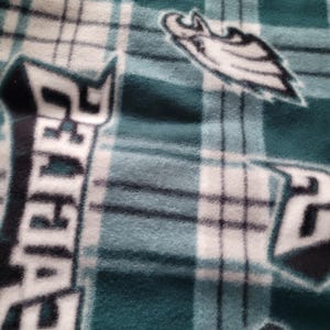 May include: Green and white plaid fleece blanket with a black and white Philadelphia Eagles logo.