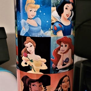 May include: A tall, cylindrical water bottle featuring images of Disney princesses. The bottle has a blue base and lid, with a yellow handle. The princesses include Cinderella, Snow White, Belle, Ariel, and others. The bottle is designed for hydration.