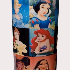 May include: A tall, cylindrical water bottle featuring images of Disney princesses. The bottle has a blue top and base, a yellow handle, and a series of princess portraits, including Cinderella, Snow White, and Ariel.