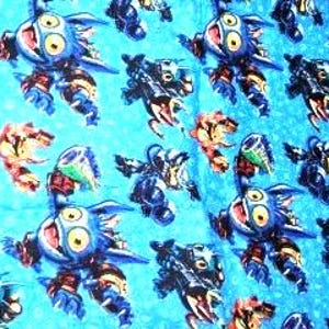 May include: A blue fabric with a repeating pattern of cartoon robots in various colors. The robots have large eyes and are set against a light blue background.