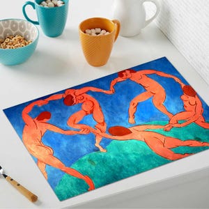May include: Rectangular placemat with a colourful artwork depicting nude figures dancing in a circle against a blue and green background. The artwork is reminiscent of a famous painting. The placemat is on a white surface.