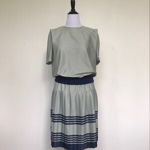May include: A green and blue polka dot dress with a pleated skirt and a navy blue waistband.