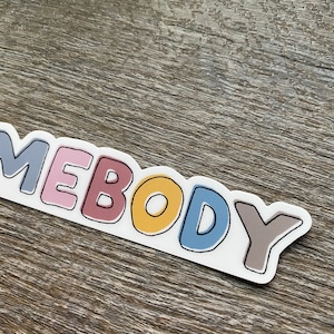May include: A sticker with the word "somebody" written in colorful, outlined letters. The letters are in shades of gray, pink, red, yellow, blue, and brown.