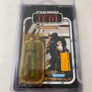 May include: A vintage Star Wars action figure of a Rebel Commando from the Return of the Jedi movie. The figure is in a plastic blister pack with a Kenner logo and the words "Star Wars Return of the Jedi" on the front.