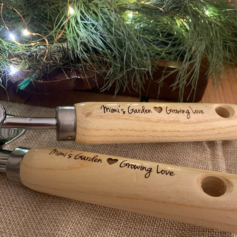 May include: Two wooden gardening tools with a heart and the text "Mimi's Garden Growing Love" engraved on the handles.
