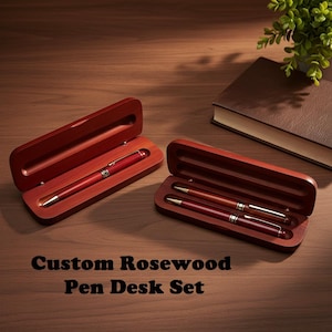 May include: A custom rosewood pen desk set featuring a red pen in an open wooden case, and two pens in another case. The text "Custom Rosewood Pen Desk Set" is at the bottom of the image.