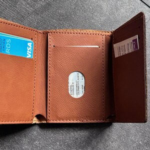 May include: A brown leather wallet with a card slot and a clear plastic window for identification. The wallet has a VISA logo and the text "UNION RDS" on a blue card inside.