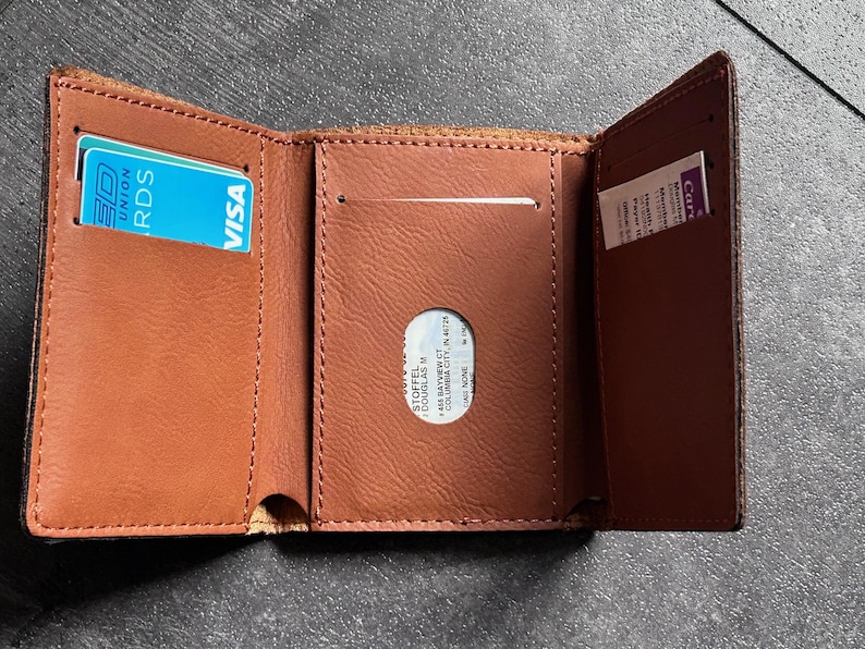 May include: A brown leather wallet with a card slot and a clear plastic window for identification. The wallet has a VISA logo and the text "UNION RDS" on a blue card inside.