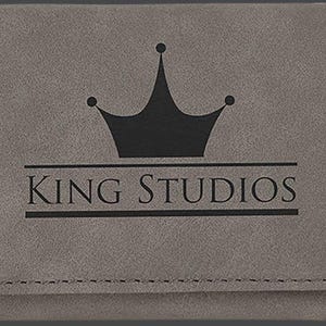 May include: Gray leather wallet with a black crown and the text "KING STUDIOS" embossed on the front.