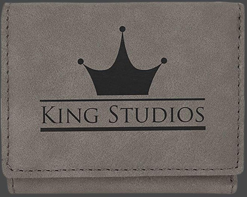May include: Gray leather wallet with a black crown and the text "KING STUDIOS" embossed on the front.
