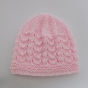 Op de afbeelding: Een roze gebreide baby muts met een textuurpatroon.