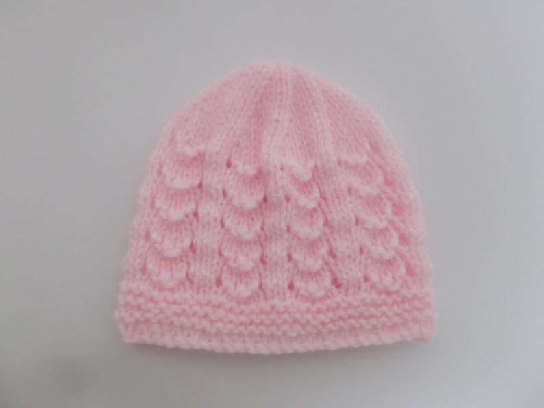 Op de afbeelding: Een roze gebreide baby muts met een textuurpatroon.