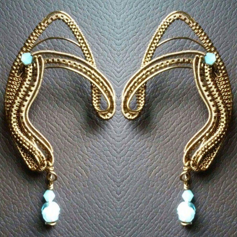 May include: A pair of gold wire ear cuffs with turquoise gemstones and dangling turquoise teardrop crystals.