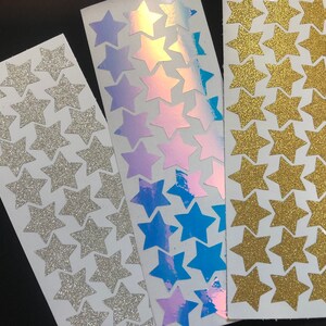 Puede incluir: Tres hojas de pegatinas de estrellas. Una hoja tiene estrellas de purpurina plateadas, otra tiene estrellas de purpurina doradas y la &uacute;ltima tiene estrellas iridiscentes con un efecto arco&iacute;ris.