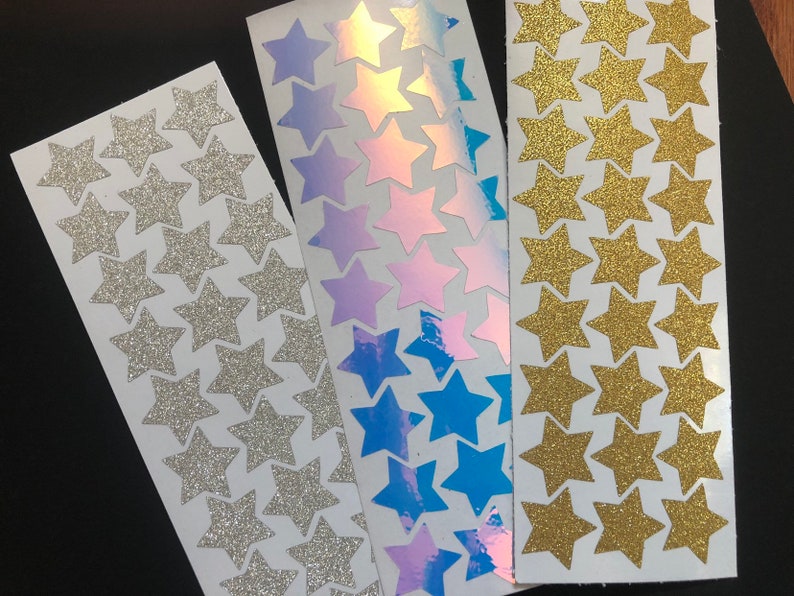 Puede incluir: Tres hojas de pegatinas de estrellas. Una hoja tiene estrellas de purpurina plateadas, otra tiene estrellas de purpurina doradas y la &uacute;ltima tiene estrellas iridiscentes con un efecto arco&iacute;ris.