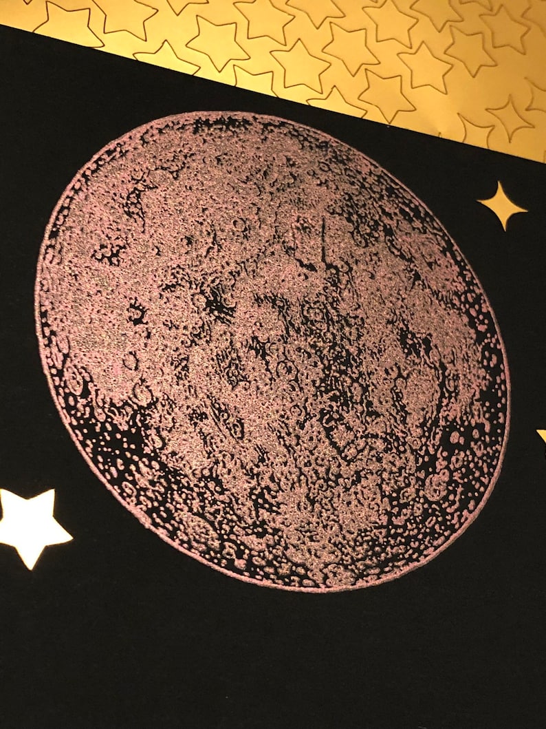 Puede incluir: Primer plano de una luna rosa brillante sobre un fondo negro. La luna es una ilustraci&oacute;n detallada con cr&aacute;teres y otras caracter&iacute;sticas de la superficie.