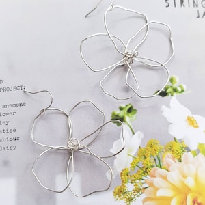 May include: A pair of silver wire earrings shaped like flowers. The earrings are delicate and have a simple design.