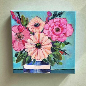 May include: A square canvas painting featuring a vibrant floral arrangement. The bouquet includes pink and peach flowers with green leaves, set against a light blue background. The flowers are in a blue and white striped vase.
