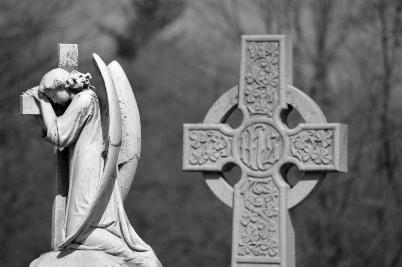 Puede incluir: Una fotograf&iacute;a en blanco y negro de una estatua de &aacute;ngel de piedra con alas, arrodillada y rezando frente a una cruz celta.