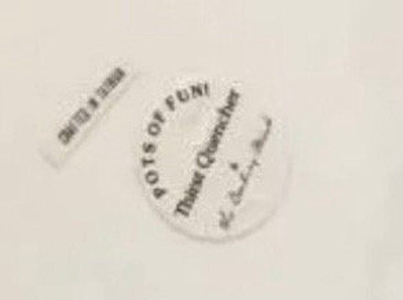 Puede incluir: Posavasos blanco y circular con el texto "Pots of Fun! Thirst Quencher" y una etiqueta rectangular m&aacute;s peque&ntilde;a que dice "Crafted in Taiwan". El posavasos tiene un borde festoneado.