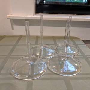 May include: Four clear glass stems with circular bases and a bamboo-like texture on the vertical shafts. Each stem features a smooth, flat, round base and a slender, upright column with subtle segmented detailing resembling natural bamboo stalks.