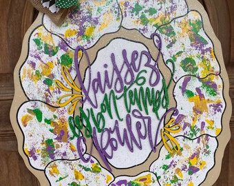 May include: A purple, green, and gold Mardi Gras wreath with the words "Laissez les bon temps rouler" in purple lettering.