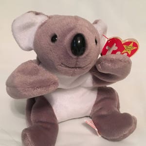 May include: Gray and white plush koala bear with a red heart-shaped tag that says "Beanie Babies".
