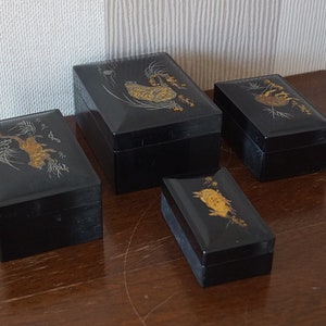 May include: Four black lacquered boxes with gold and silver painted designs. The boxes are of varying sizes and feature different Japanese-inspired motifs.