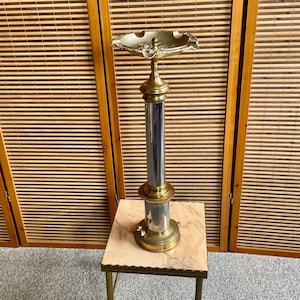 Vintage shiny metal ashtray stand, vintage ashtray with an eagle and tiger decoration at the base.