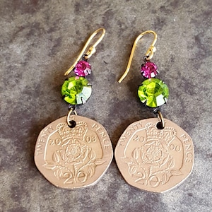 May include: A pair of earrings featuring a 2003 twenty pence coin with a green and pink crystal embellishment.