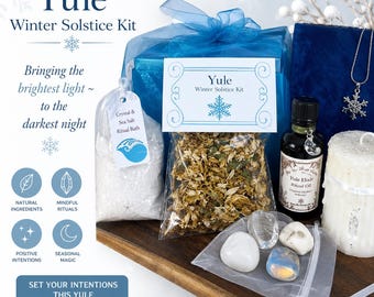 May include: A Yule Winter Solstice Kit with a blue ribbon, containing a bag of sea salt, a bag of herbs, a bottle of ritual oil, crystals, and a snowflake pendant. The kit includes text that says "Set Your Intentions This Yule."
