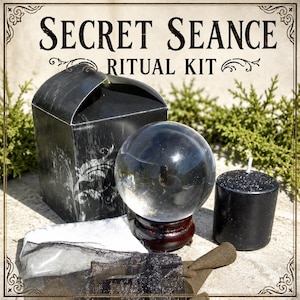 May include: A black ritual kit with the text "SECRET SEANCE RITUAL KIT". The kit includes a crystal ball on a wooden stand, a black candle, a black box, and other ritual items.
