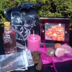 May include: A pink candle, a bottle of pink liquid with a silver pentagram charm, a small bag of brown incense cones, a pink and white organza bag, a pink and white organza bag, a small picture frame with a photo of a pile of pumpkins, and five pink and brown stones.