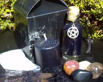 May include: A black gift box with bat-wing shaped flaps, a small black pillar candle, a clear glass bottle filled with dark blue liquid and a silver pentacle charm, three polished stones, and a black mesh bag containing brown incense cones.