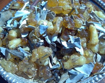 May include: A silver-edged dish containing a mixture of amber resin pieces, dried herbs, and sage leaves. The resin pieces are various sizes and shapes, some translucent. The sage leaves are a muted grey-green, and the herbs are a mix of green and brown.