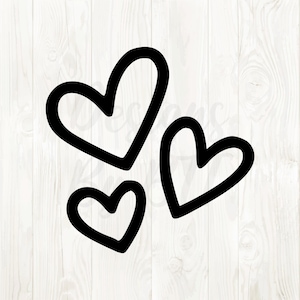 Può includere: Tre cuori neri di diverse dimensioni sono disposti su uno sfondo di legno bianco. I cuori hanno un design semplice e delineato, creando un'estetica minimalista e moderna. L'immagine è adatta per San Valentino o altri temi romantici.