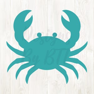 May include: A teal crab silhouette with large claws and multiple legs. The crab is centered on a white wood grain background. The text "Designs By BTI" is partially visible in the background.