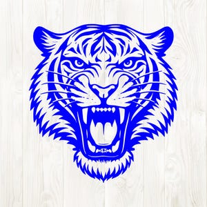 May include: A blue illustration of a tiger's head, featuring an open mouth with visible teeth. The tiger's face is detailed with stripes and fur, set against a white wood-grain background. The design is bold and graphic.