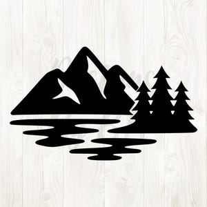 May include: Black silhouette of a mountain range with three pine trees and a lake. The design features a simple, clean aesthetic, perfect for nature-themed crafts or decor. The image is set against a light wood grain background.