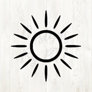 Op de afbeelding: Een zwart zonontwerp met een cirkelvormig midden en stralende lijnen. De zonnegrafiek staat tegen een witte, houtnerf achtergrond, wat een eenvoudige maar opvallende visuele uitstraling creëert.