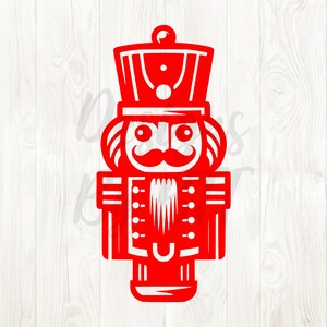May include: A red, cut-out design of a traditional nutcracker soldier. The design features a tall hat, a handlebar mustache, and a uniform with buttons. The image is a festive holiday decoration.