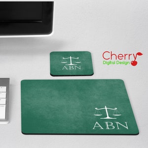 Pode incluir: Um conjunto de tapete de rato e base para copos verdes com um desenho de balança da justiça branca e as letras "ABN". O tapete do rato é retangular e a base do copo é quadrada. O conjunto está sobre uma superfície branca. O logótipo Cherry Digital Design está no canto superior direito.