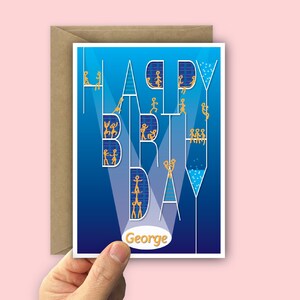 A birthday card with a blue gradient background and the words "HAPPY BIRTHDAY" in white and connected. The letters are filled with yellow stick figures having fun. Your recipient's name, in a yellow, in a white oval which radiates light like spotlights through the design. The card is held open by a hand over a recycled brown envelope and a light pink background.