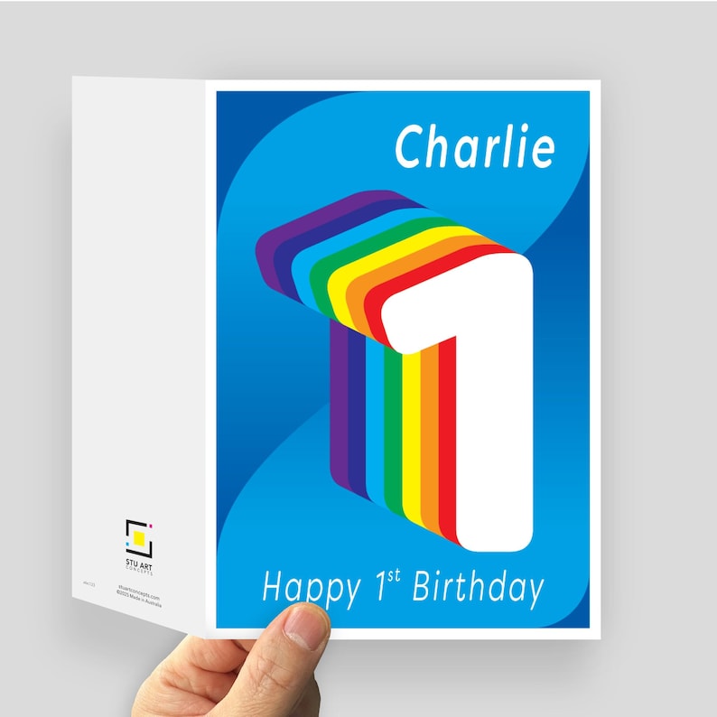 May include: A folded greeting card with a blue background featuring a large white number one with a rainbow-colored layered side profile. The text reads Charlie at the top and Happy 1st Birthday at the bottom. A small logo is visible on the side.