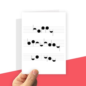 May include: A white greeting card featuring black musical staff lines and notes arranged to spell out the words "happy birthday to you". The design uses circular and semi-circular black shapes to form the letters against the horizontal lines.